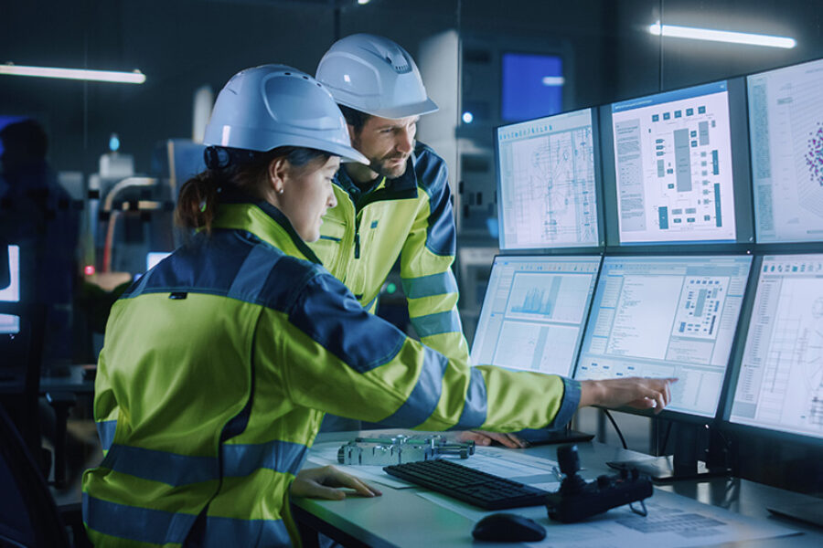 Industry 4.0 Modern Factory: Project Engineer Talks to Female Operator who Controls Facility Production Line, Uses Computer with Screens Showing AI, Machine Learning Enhanced Assembly Process